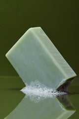 A green soap in still with a dash of bubbles at the bottom